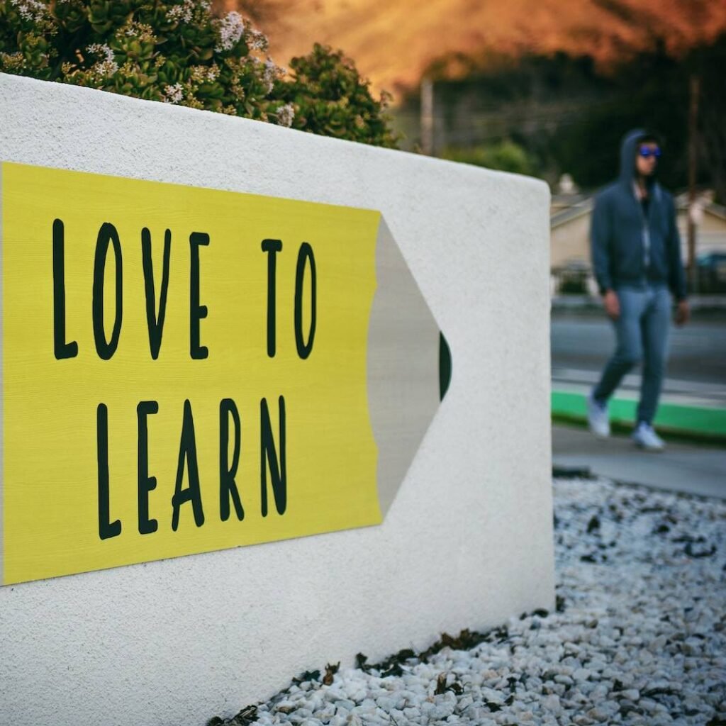 love to learn pencil signage on wall near walking man