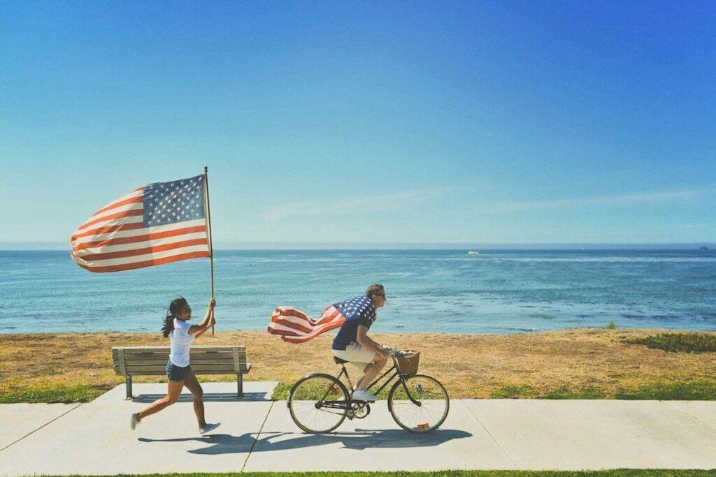 man riding bike and woman running holding flag of USA